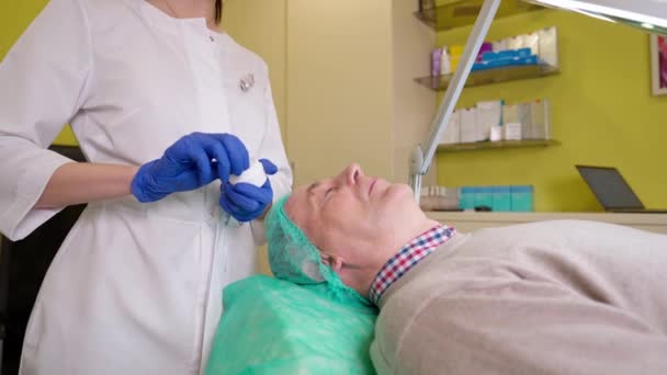 Doctor preparing skin of mature patient before skin biorevitalization procedure — Stock Video