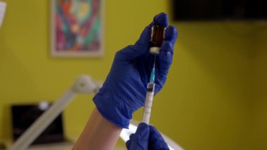 Güzellik uzmanı klinikte güzellik iğnesinden önce şırıngayı ilaçla dolduruyor.