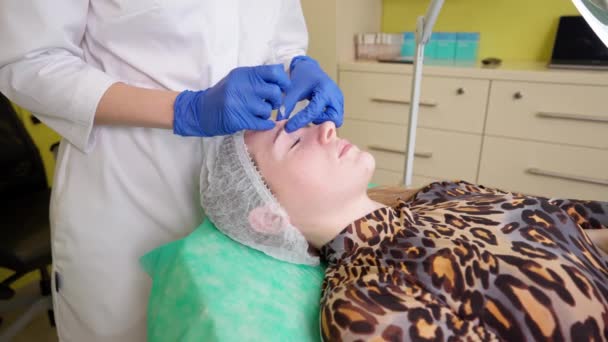 Professional cosmetologist doing xeomin injections for young woman visiting beauty salon — Stockvideo