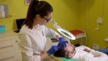 Kozmetik uzmanı, mesoterapi işleminden önce erkek kafasına anestezi uyguluyor.