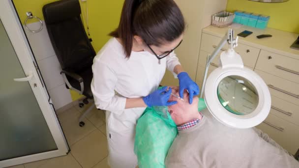 Mujer joven en guantes haciendo belleza anti edad inyección para hombre mayor durante el tratamiento de biorevitalización — Vídeo de stock