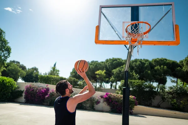 Male sportsman playing basketball throwing the ball at playgroun