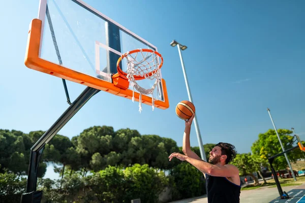 Male sportsman playing basketball throwing the ball at playgroun