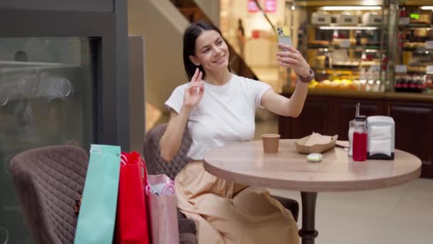 Vonzó nő szelfit készít a kávézóban vásárlás után a plázában — Stock videók