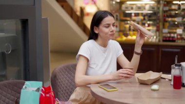 Esmer kadın alışveriş merkezinde yorucu bir günün ardından kahve molası veriyor.