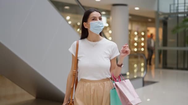 Mujer joven en máscara facial médica caminando en el centro comercial — Vídeo de stock