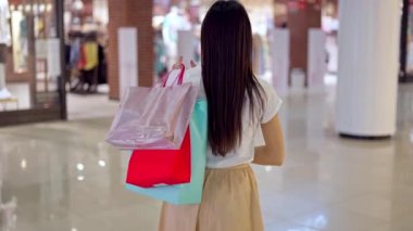 Alışveriş merkezlerinde alışveriş torbalarıyla gezen bir kadın.