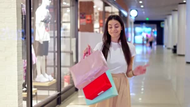 Emocionado blogger de moda mostrando bolsas de papel con compras mientras está de pie en el centro comercial — Vídeos de Stock
