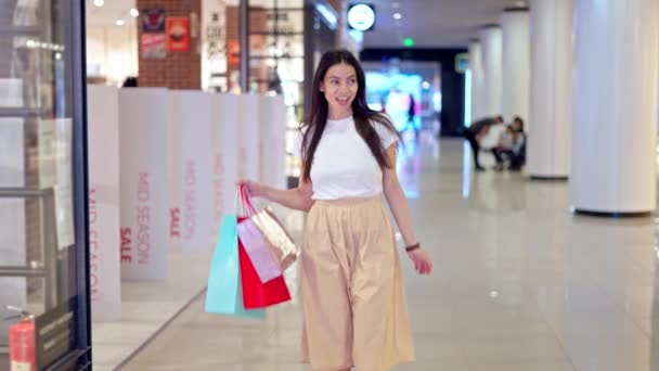 Nadšený žena se dostává z módního obchodu s mnoha nákupních papírových tašek — Stock video
