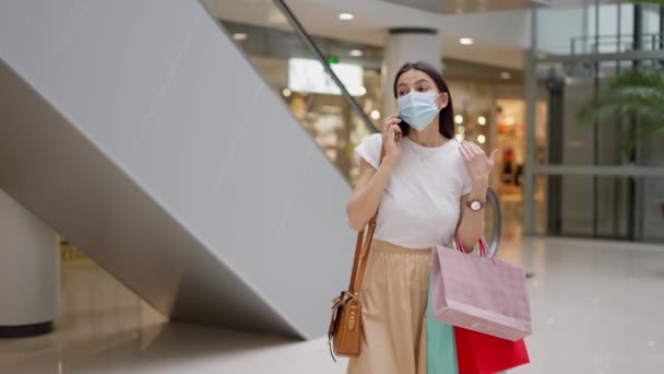 Feminino em máscara protetora falando no telefone no shopping — Vídeo de Stock