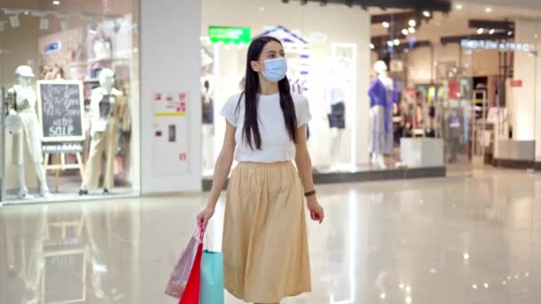 Donna in maschera medica con borse a piedi nel centro commerciale — Video Stock