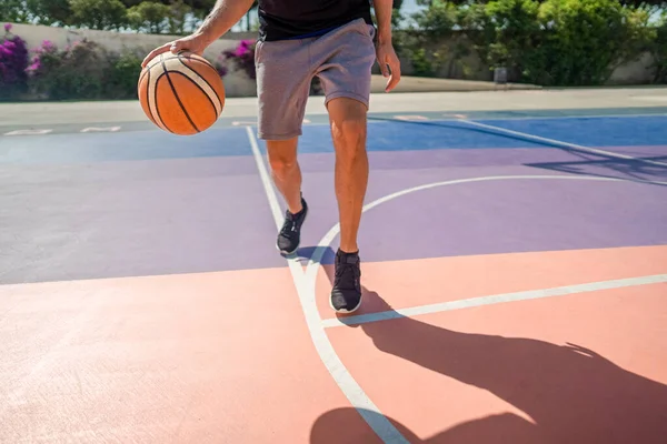 Legs of a professional basketball player dribbling the ball on the basketball field — Stock Photo, Image