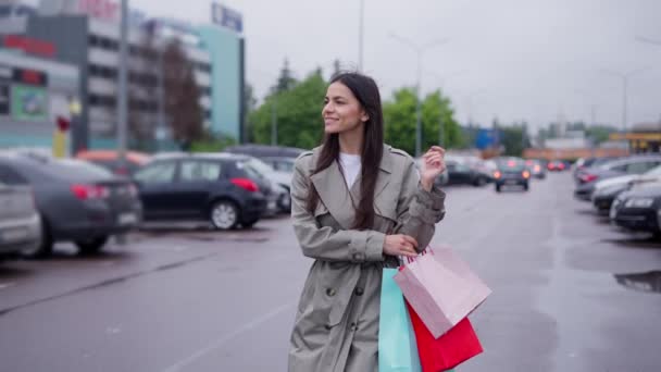 Vrouwelijke shopaholic met tassen lopen langs parkeerplaats naar haar auto — Stockvideo