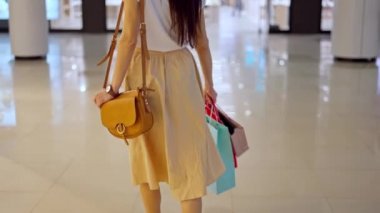 Bir sürü alışveriş çantası olan bir kadın alışveriş merkezinde vitrinlere bakıyor.