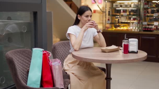Mujer bebiendo café en la cafetería después de ir de compras al centro comercial — Vídeos de Stock