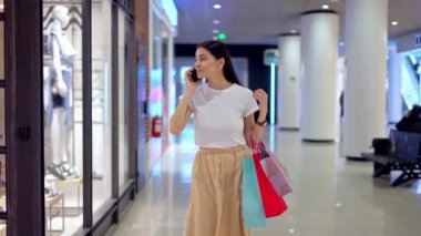 Alışveriş meraklısı bir kadın alışveriş merkezinde dolaşırken arkadaşını arıyor.