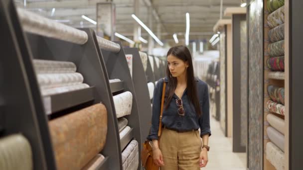 Ung kvinnlig kund tittar på stort sortiment av tapeter för heminredning — Stockvideo