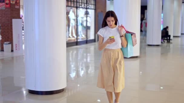 Jovem mulher usando o aplicativo de navegação no telefone para encontrar loja no shopping — Vídeo de Stock