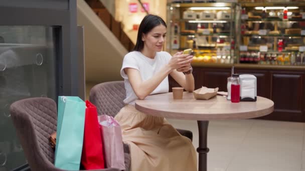 Femme bavarder avec son ami à la cour de nourriture tout en se relaxant après avoir fait du shopping dans le centre commercial — Video