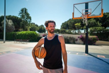 Basketbolcu yazın açık havada basketbol sahasında duruyor.