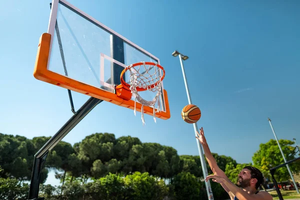 Male sportsman playing basketball throwing the ball at playground