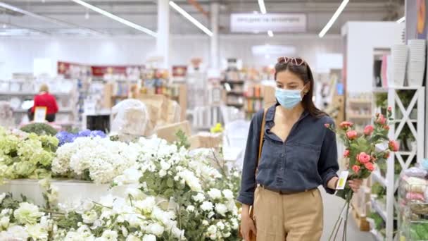 Молодая женщина покупает искусственные цветы для домашнего декора — стоковое видео