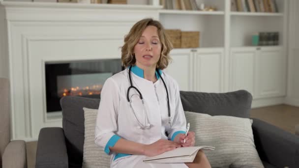 Щаслива жінка-лікар дає онлайн-консультацію пацієнту через відеоконференцію на ноутбуці — стокове відео
