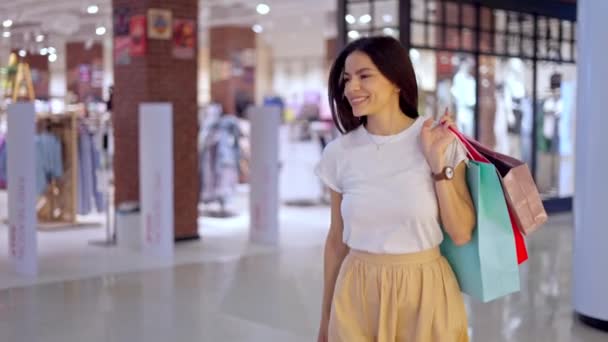 Mujer feliz dejando la tienda en el centro comercial con muchas bolsas de papel llenas de compras — Vídeos de Stock