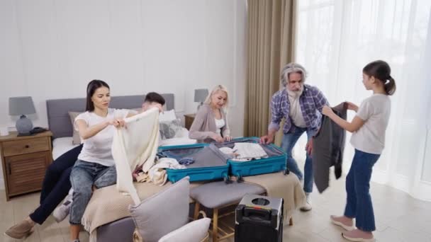 Familjen hjälper farfar att packa kläder i resväskan före flygresan — Stockvideo