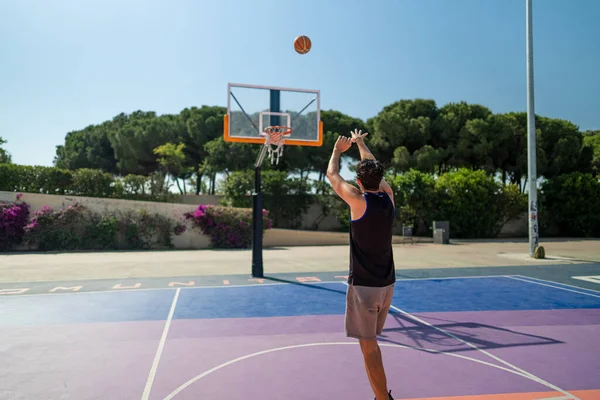 Male sportsman playing basketball throwing the ball at playgroun