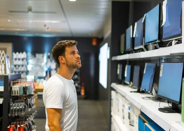 Cliente masculino enfocado que elige monitor en tienda — Foto de Stock