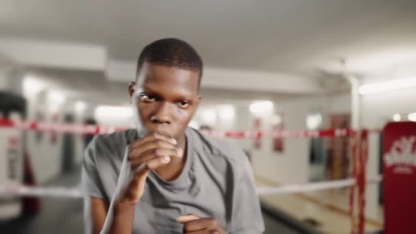 在体育馆进行拳击训练的过程中，年轻的有动力的非洲运动员拳击手向镜头扔拳 — 图库视频影像