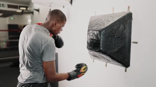 Jovem focado homem africano boxeador praticando socos enquanto treinava no clube de luta — Vídeo de Stock