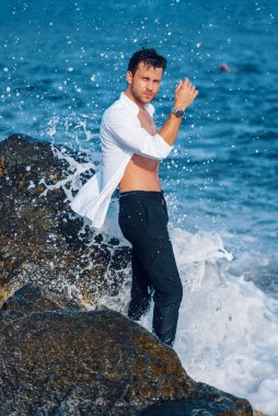 Deniz kıyısında dalgalanan yakışıklı adam.