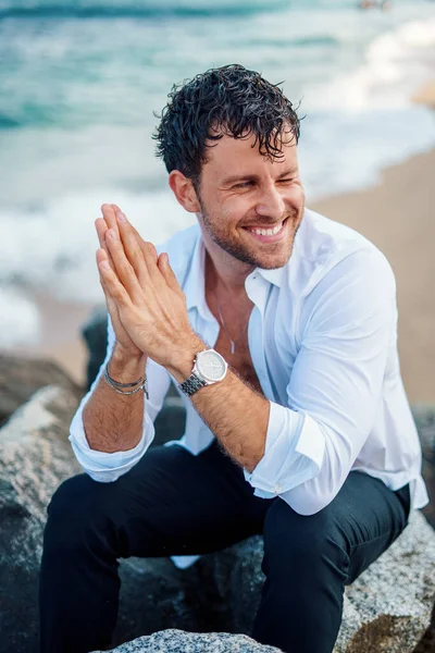 Przystojny mężczyzna uśmiechający się na skalistym wybrzeżu — Zdjęcie stockowe