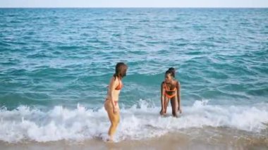 Deniz dalgalarında süzülen bir çift güzel kız.