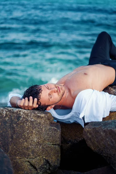 Relajado hombre acostado en la roca en la playa —  Fotos de Stock