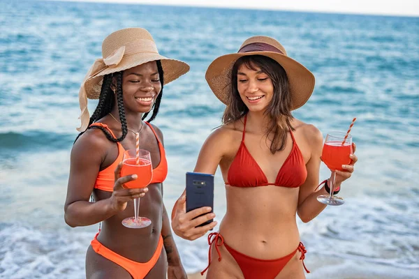 Novias con cócteles y smartphone en la playa — Foto de Stock