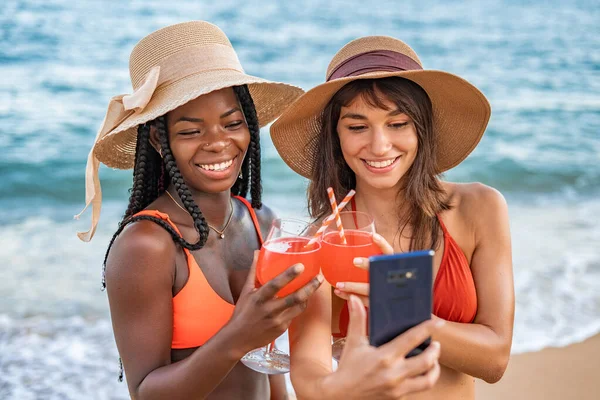 Encantada diversas namoradas com coquetéis tomando selfie perto do mar — Fotografia de Stock