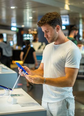 Elektronik mağazasında akıllı telefonu olan bir alıcı.