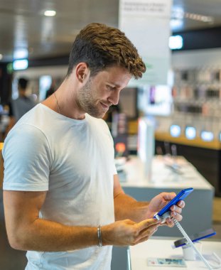 Gülümseyen müşteri akıllı telefonu test ediyor.
