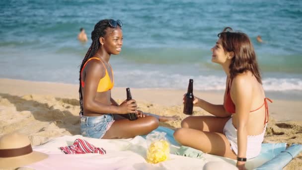 Due ragazze migliori amici seduti sulla spiaggia di sabbia dal mare — Video Stock