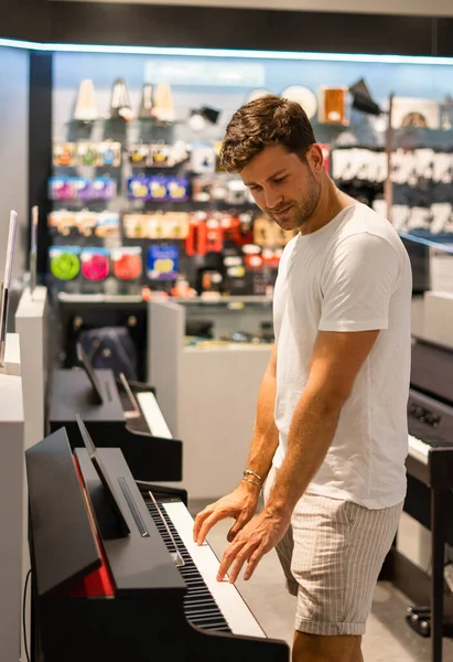 Homem escolhendo piano eletrônico na loja — Fotografia de Stock