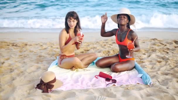 Dwóch najlepszych wielorasowych przyjaciół siedzących na letniej plaży — Wideo stockowe