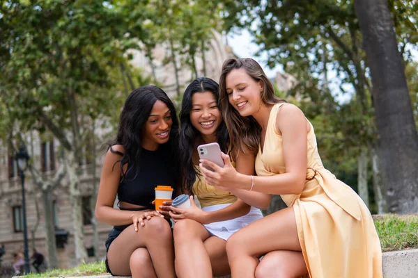 Namoradas multiétnicas com smartphone e café na cidade — Fotografia de Stock
