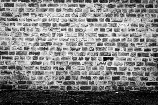 Old black and white brick wall with pavement 2 — Stock Photo, Image