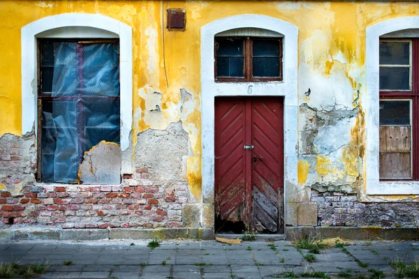 Alte beschädigte Mauer mit vergitterten Fenstern und einer Tür 1 — Stockfoto