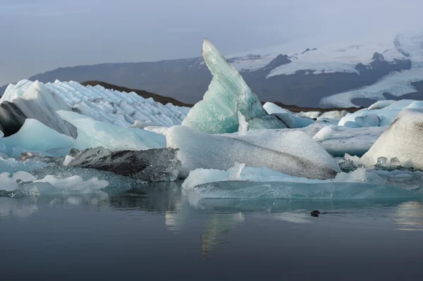 Cubi di ghiaccio nella laguna del ghiacciaio di Jokulsarlon con lo sfondo della catena montuosa della neve — Foto Stock