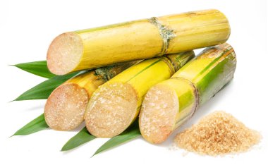 Şeker kamışı kesikleri ve beyaz arkaplanda izole edilmiş kahverengi şeker yığını.