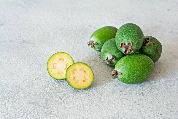 Feijoa, exotic (tropical) fruit, berry of the myrtle family, grows in the tropics and subtropics. Ripe green feijoa berries on a gray background.